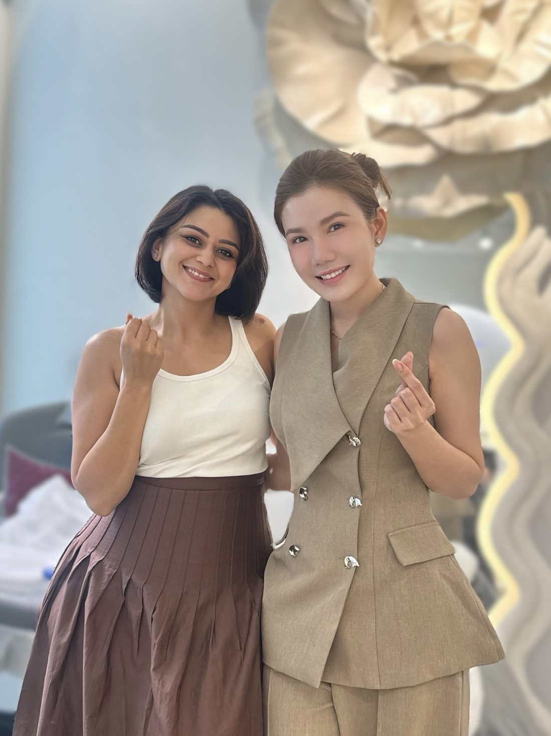 Smiling client and Master Coco Le making finger hearts in the COCO BROW studio