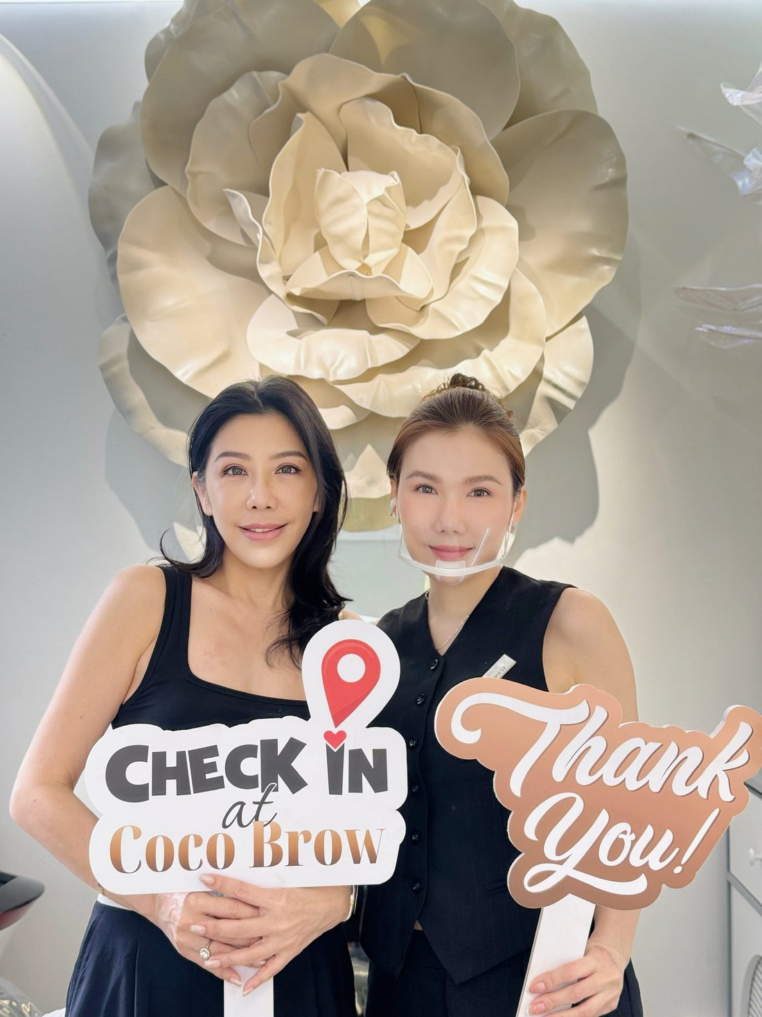 Client holding a Check in at Coco Brow board next to Master Coco Le