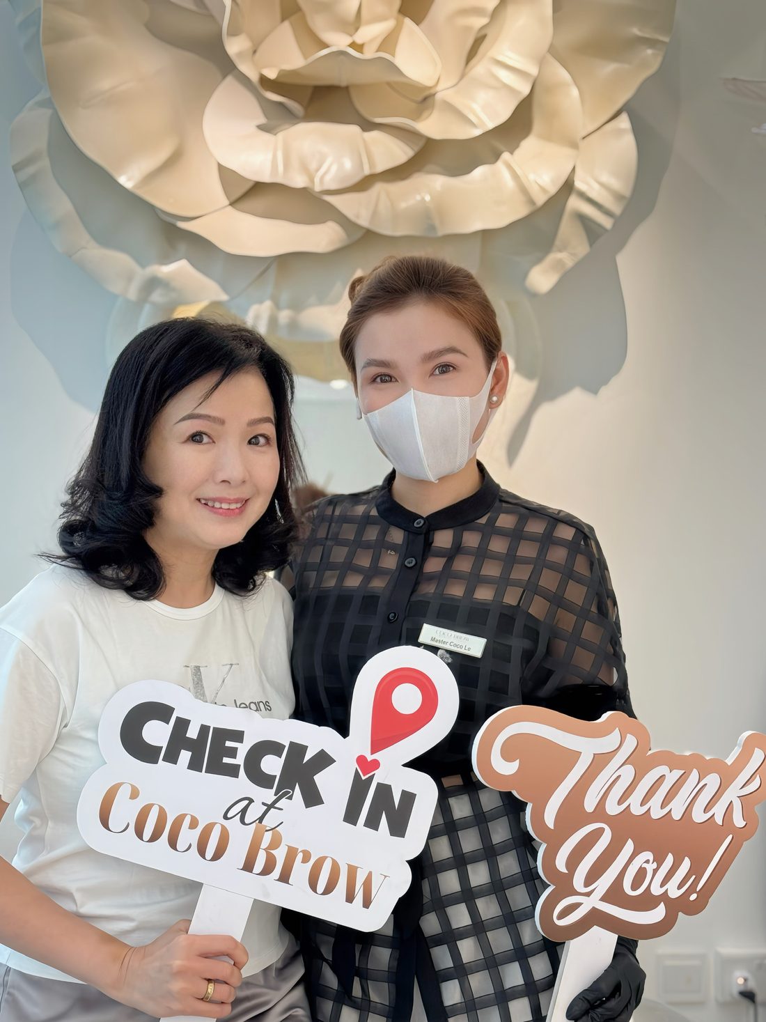 Client holding a Check in at Coco Brow board with Master Coco Le at the studio